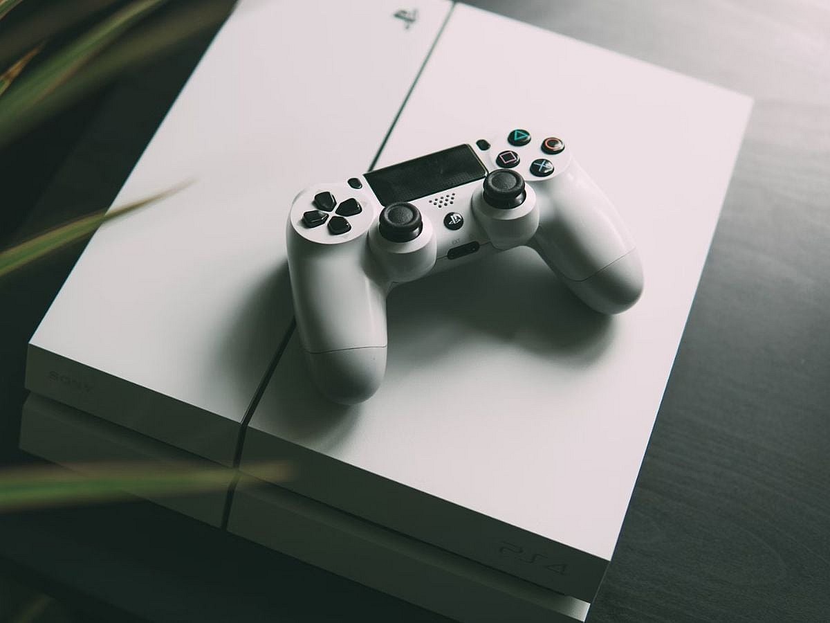 PlayStation 4 PS4 on table with plant Nikita Kachanovsky Unsplash