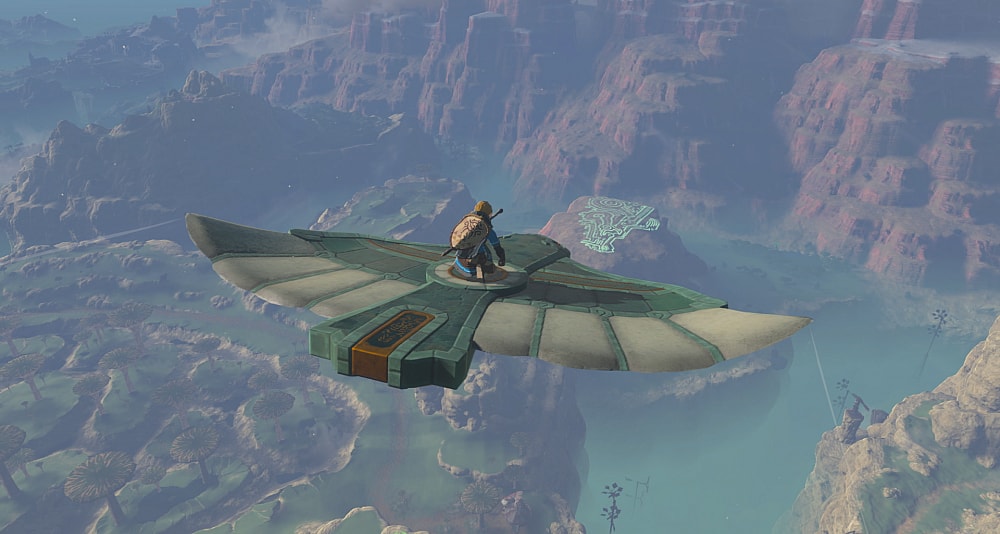 Link soars above the land on a bird statue. The land below shows small windmills, giant mushroom-like trees, and glowing geoglpyhs via The Legend of Zelda: Tears of the Kingdom (2023), Nintendo