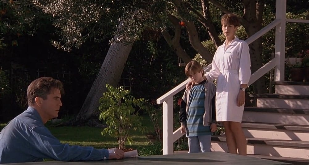 A woman and a boy look at a man.