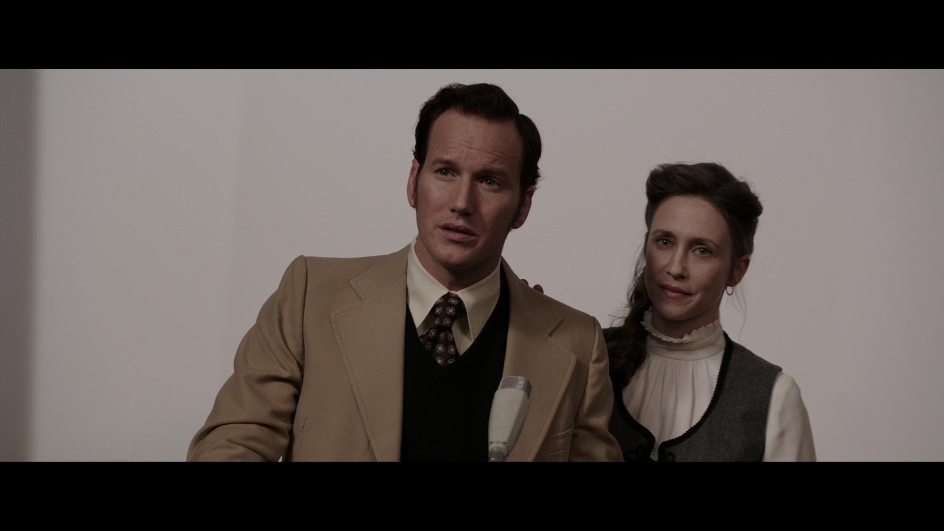 Ed (Patrick Wilson) and Lorraine (Vera Farmiga) Warren field questions regarding their work in The Conjuring (2013), New Line Cinema