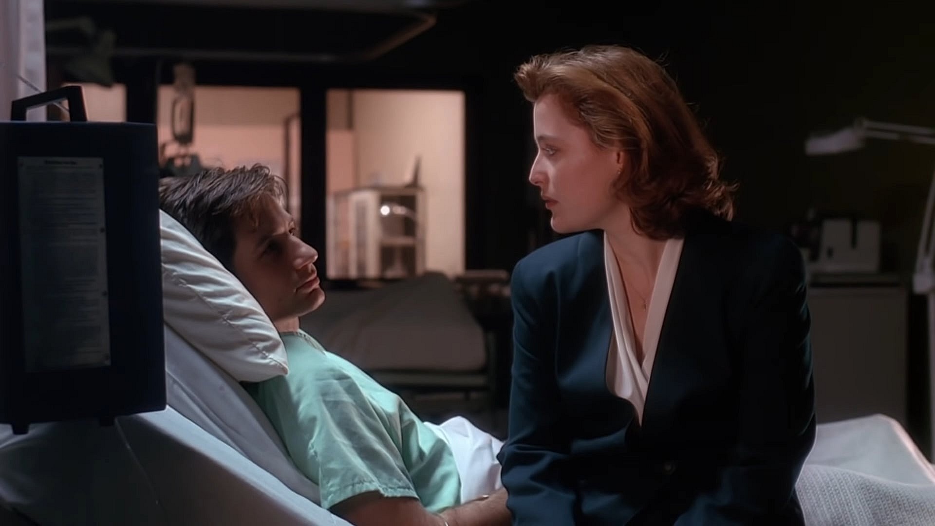 Agent Scully (Gillian Anderson) checks in on Agent Mulder (David Duchovny) in The X-Files Season 1 Episode 13 "Beyond the Sea" (1994), 20th Century Studios