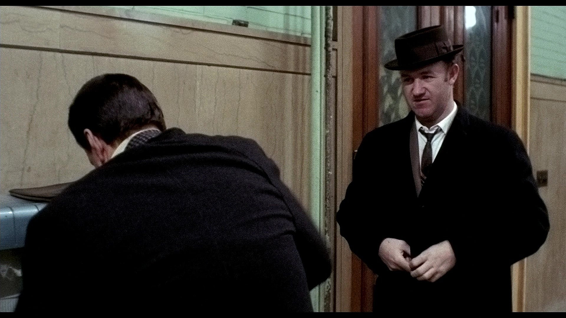 Jimmy "Popeye" Doyle (Gene Hackman) taunts Buddy "Cloudy" Russo (Roy Scheider) over his recent injury in The French Connection (1971), 20th Century Studios