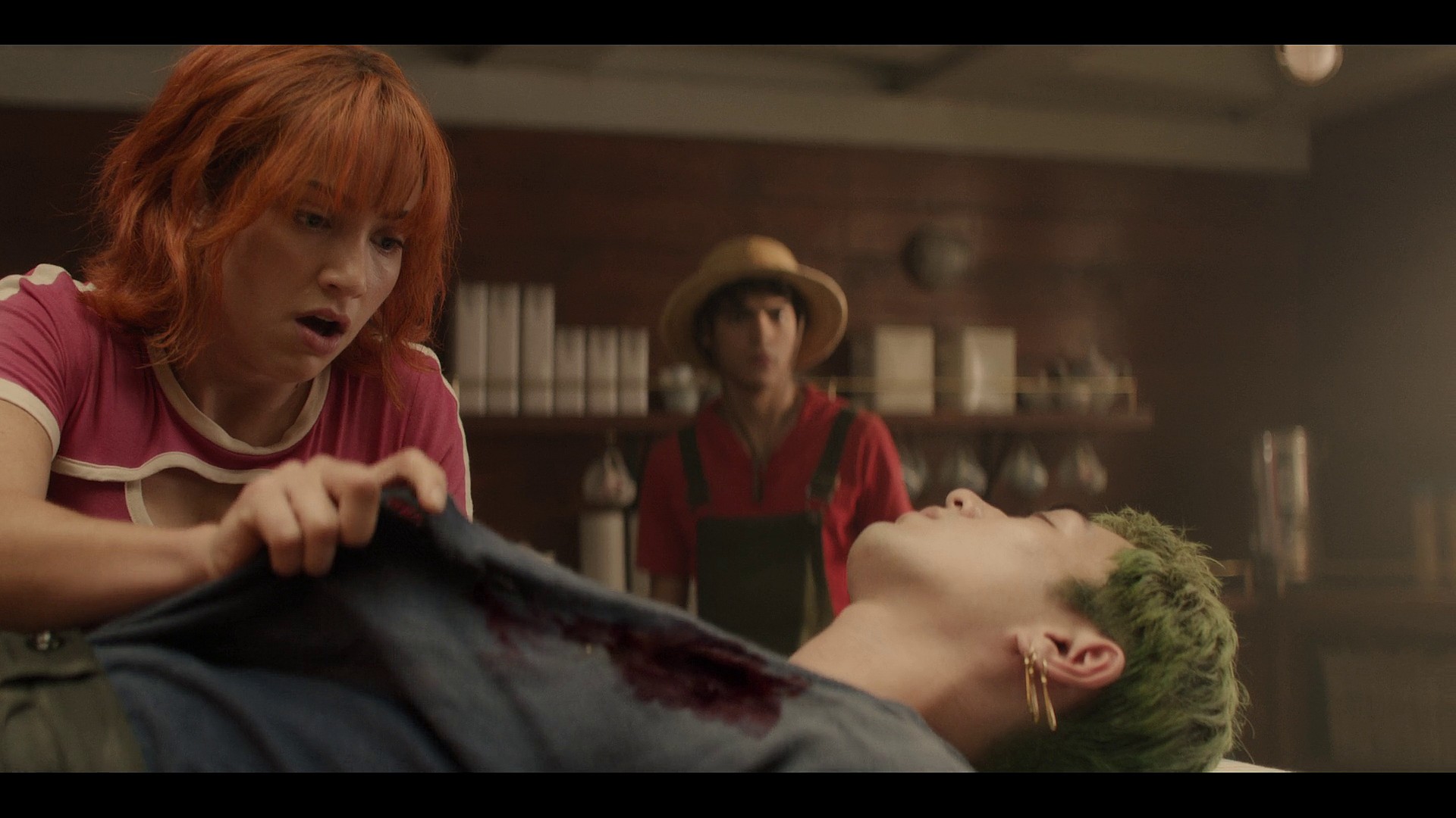 Nami (Emily Rudd) and Luffy (Iñaki Godoy) take stock of Zoro's (Maceknyu) wound in One Piece Season 1 Episode 6 "The Chef and the Chore Boy" (2023), Netflix