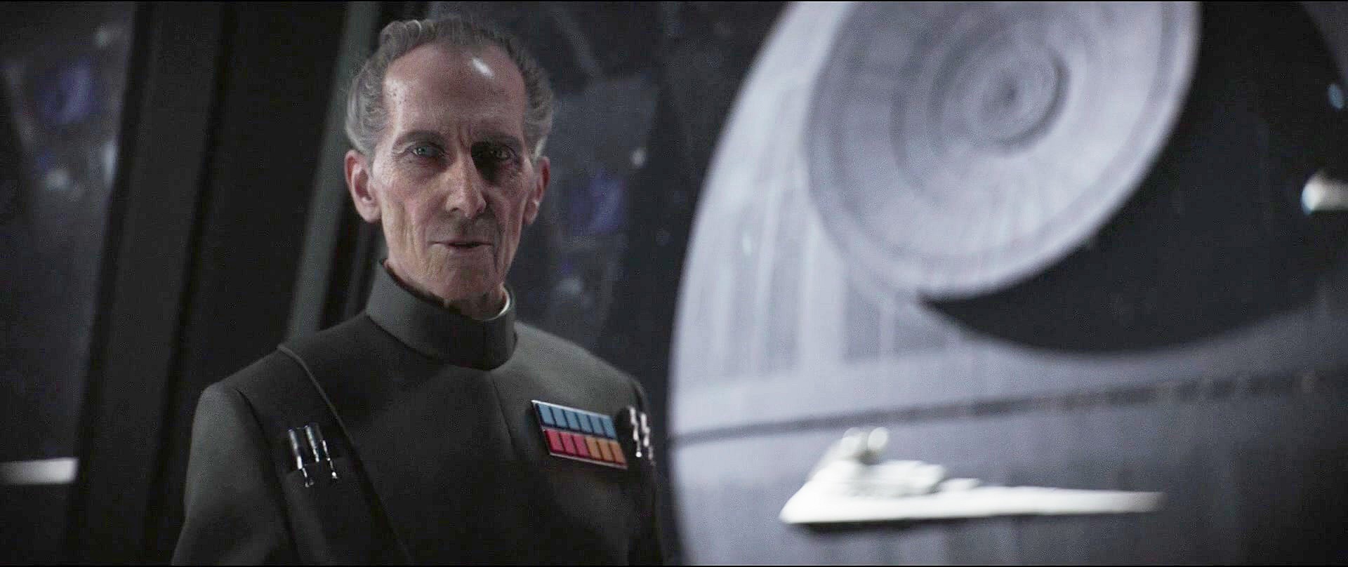 Grand Moff Tarkin (Peter Cushing) awaits an update from Director Krennic (Ben Mendelsohn) in Rogue One: A Star Wars Story (2016), Disney