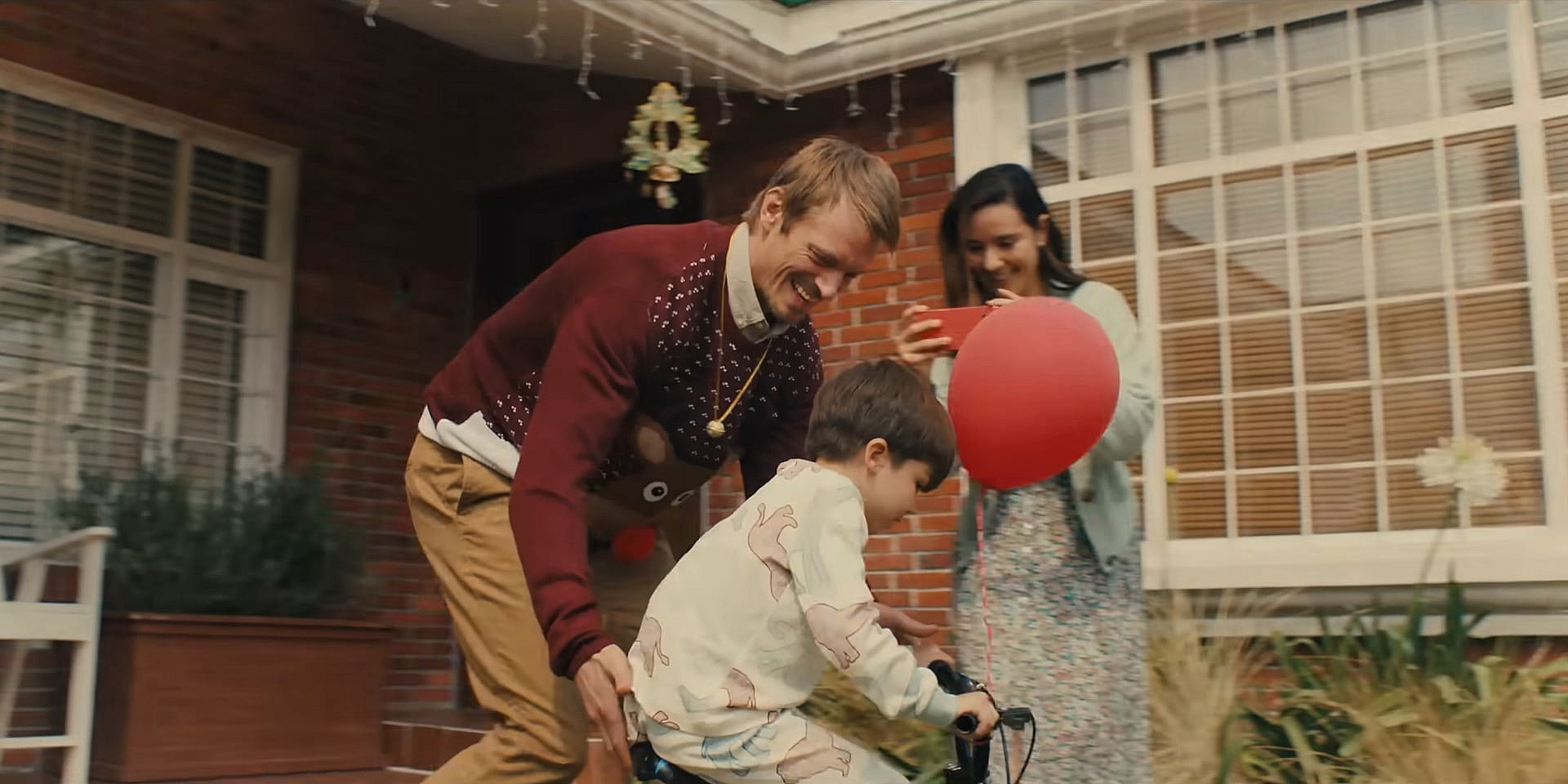 Joel Kinnaman as Brian Godlock, Catalina Sandino Moreno as Saya, and Anthony Giulietti in Silent Night (2023), Lionsgate