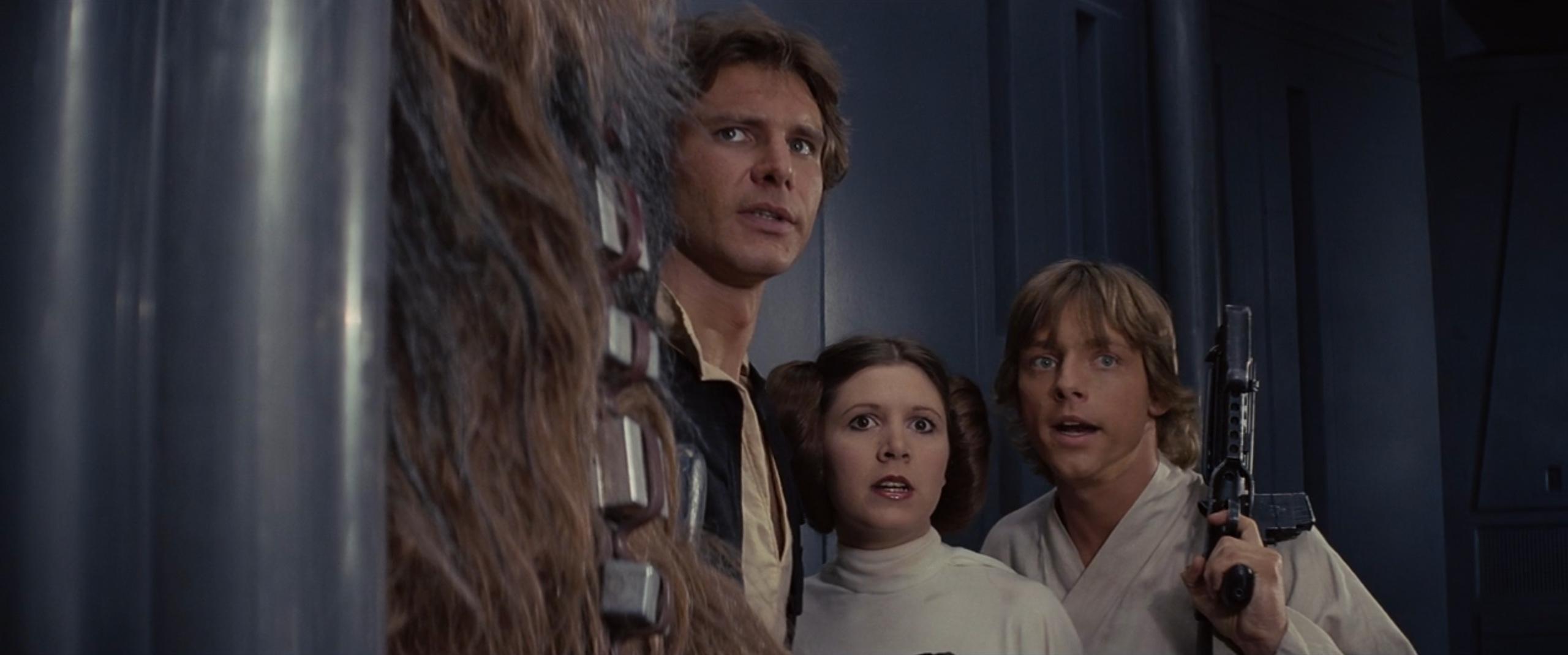 Chewbacca (Peter Mayhew), Han Solo (Harrison Ford), Princess Leia Organa (Carrie Fisher), and Luke Skywalker (Mark Hamill) plan their escape from the Death Star in Star Wars Episode IV: A New Hope (1977), Lucasfilm