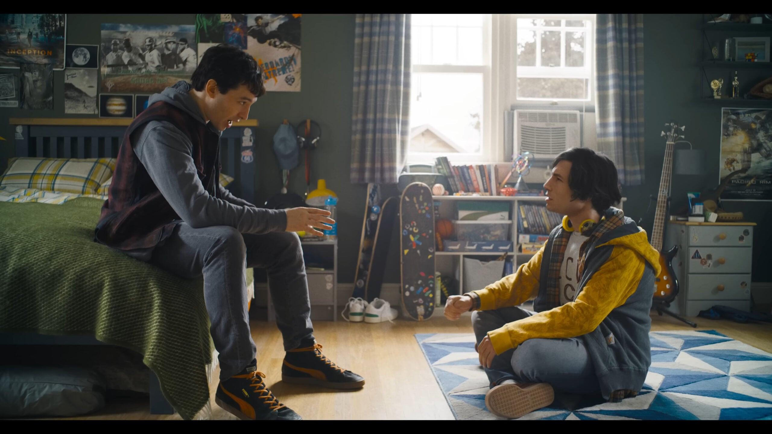 Barry Allen (Ezra Miller) explains the current situation to his past self in Batman (Michael Keaton) reveals his cache of Batsuits in The Flash (2023), Warner Bros. Pictures