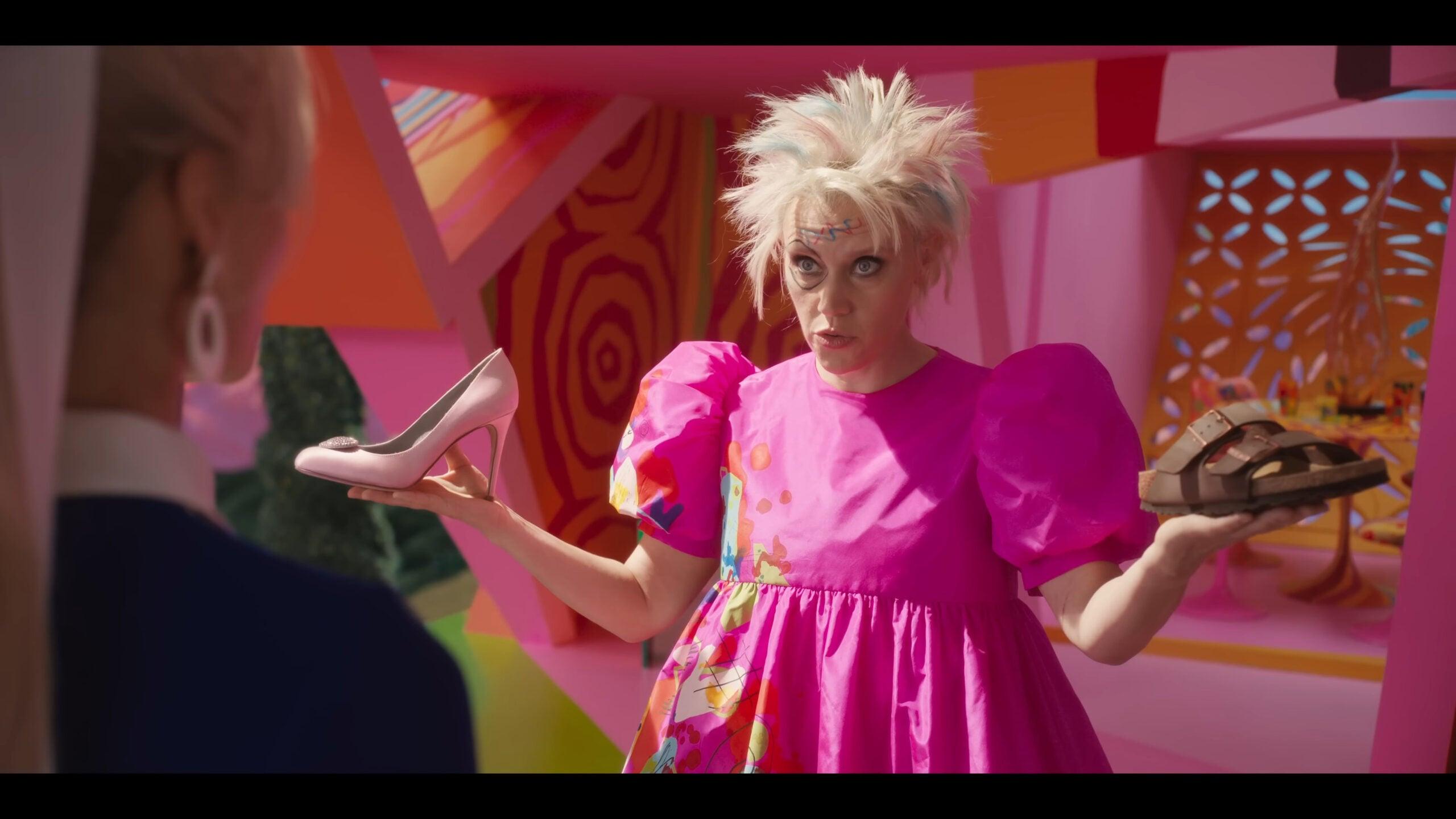 Weird Barbie (Kate McKinnon) offers Barbie (Margot Robbie) a choice in Barbie (2023), Warner Bros. Pictures