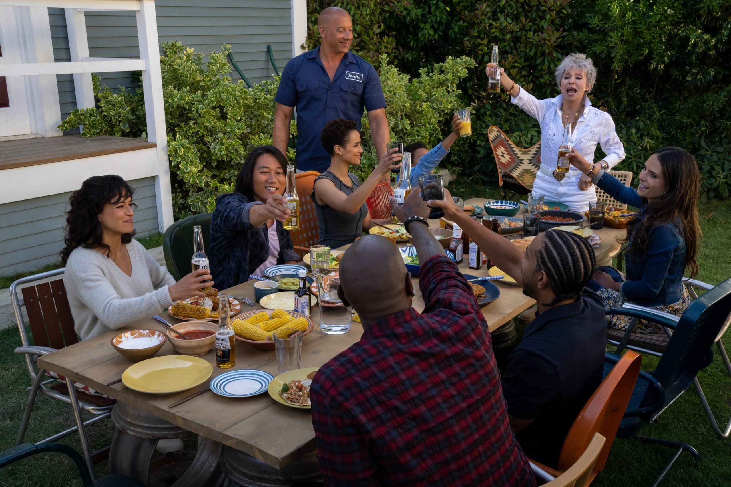 (clockwise, from left) Letty (Michelle Rodriguez), Han (Sung Kang), Ramsey (Nathalie Emmanuel), Dom (Vin Diesel), Little Brian (Leo Abelo Perry), Abuelita (Rita Moreno), Mia (Jordana Brewster), Tej (Chris ‘Ludacris’ Bridges, back to camera) and Roman (Tyrese Gibson, back to camera) in Fast X, directed by Louis Leterrier.