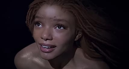Ariel (Halle Bailey) notices a naval battle above the surface in The Little Mermaid (2023), Disney