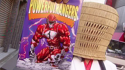 A mysterious priest (Katsuyuki Konishi) offers AkibaRed (Masato Wada) a free 'Powerful Rangers' bible in Unofficial Sentai Akibaranger Season 2, Episode 5 "Delusional Imports" (2013), Toei Co. Ltd.