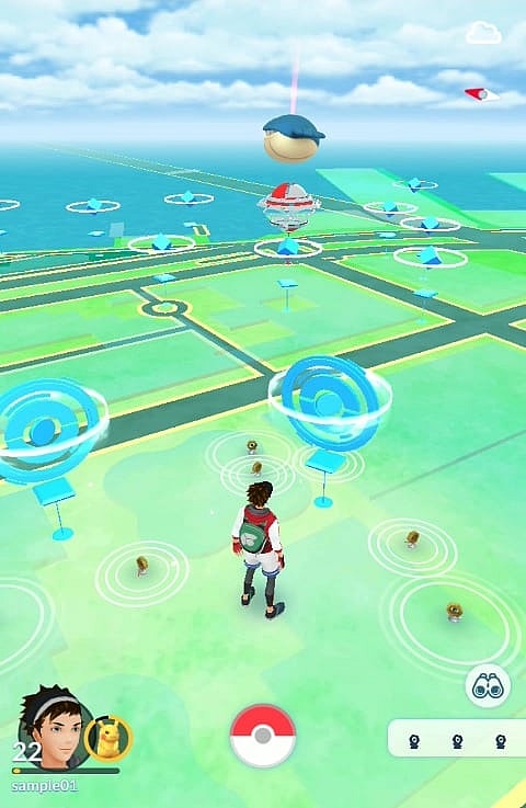 A player walks among wild Meltan, with a Wailmer in a Gym in the distance in Pokémon Go (2016), Niantic