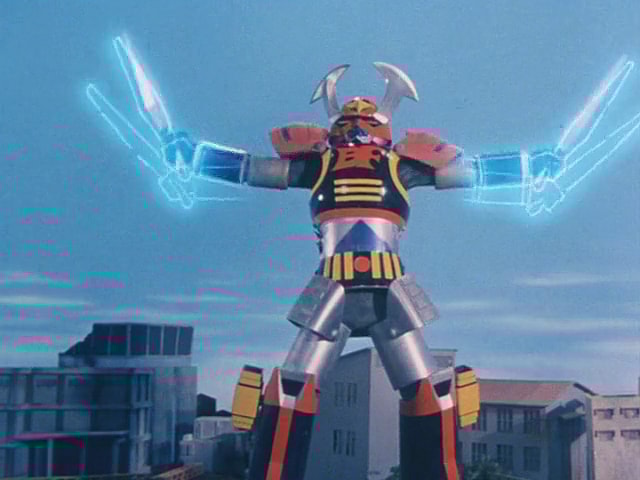 Battle Fever J marks the first appearance of a 'giant robo' in the franchise's history by deploying his Cross Fever attack against the Umbrella Monster (Teiji Omiya) in Battle Fever J Episode 5 "The Great Robot Dogfight" (1979), Toei Co. Ltd.
