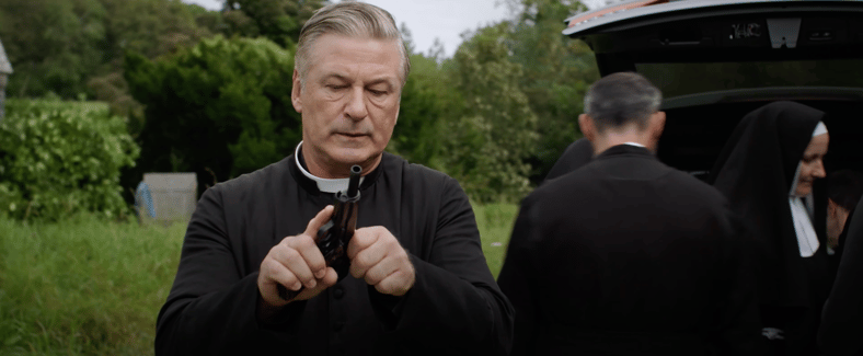 Father Hector McGrath (Alec Baldwin) checks the chamber in Pixie (2021), Paramount Pictures