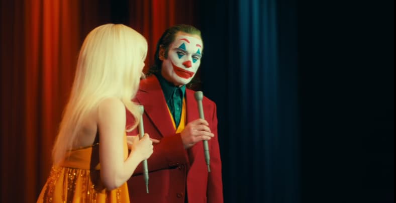 Arthur (Joaquin Phoenix) listens to Harleen (Lady Gaga) tell a joke in Joker: Folie à Deux (2024)