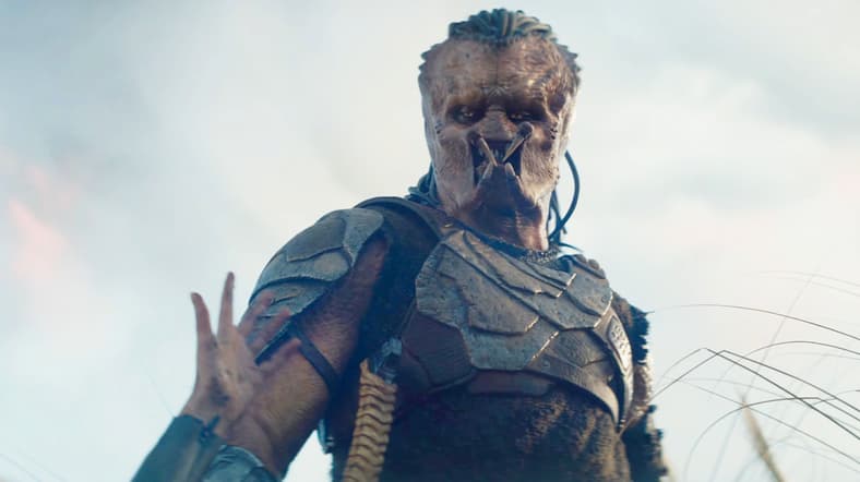 Thia (Elle Fanning) asks Dek (Dimitrius Schuster-Koloamatangi) for a helping hand in Predator: Badlands (2025), 20th Century Studios