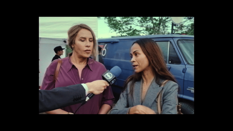 Emilia (Karla Sofía Gascón) and Rita (Zoe Saldaña) are interviewed regarding their new non-profit organization in Emilia Pérez (2024), Netflix