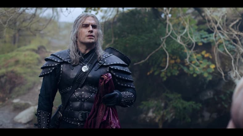 Geralt (Henry Cavill) holds Jaskier's things while the bard bathes in The Witcher Season 2 Episode