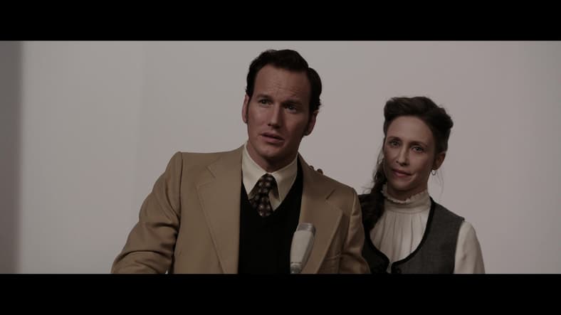 Ed (Patrick Wilson) and Lorraine (Vera Farmiga) Warren field questions regarding their work in The Conjuring (2013), New Line Cinema