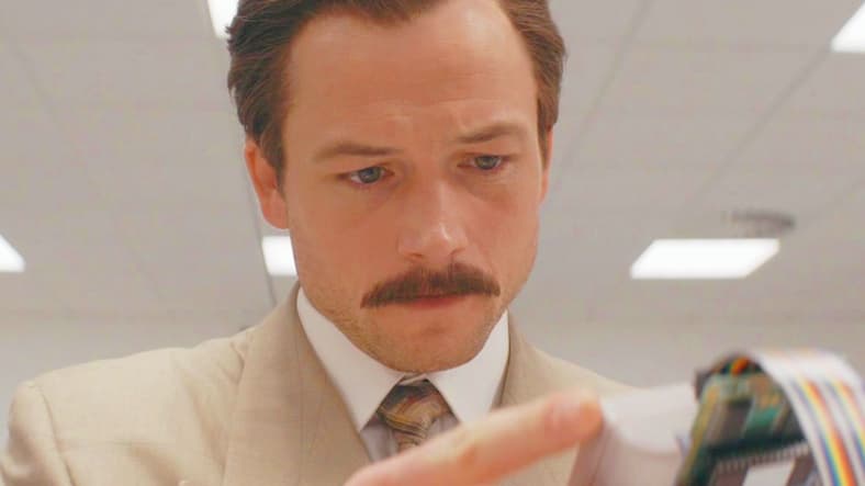Henk Rogers (Taron Egerton) tests out the Nintendo Game Boy version of the titular game in Tetris (2023), Apple