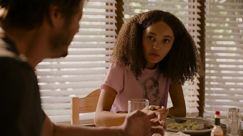 Sarah (Nico Parker) chats with her father Joel (Pedro Pascal) over breakfast in The Last of Us