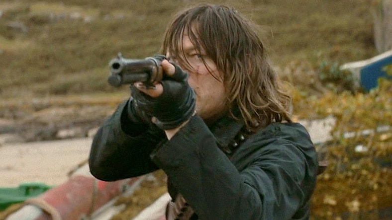 Daryl (Norman Reedus) fends off a surprise shore-side attack from a pack of Walkers in The Walking Dead: Daryl Dixon Season 3 Episode 3 "El Sacrificio" (2025), AMC