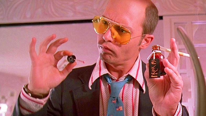 Raoul Duke (Johnny Depp) is unsure about Dr. Gonzo's (Benicio Del Toro) anxiety remedy in Fear and Loathing in Las Vegas (1998), Universal Pictures