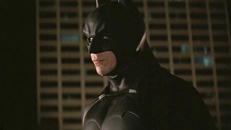 Batman (Christian Bale) vows to help Lt. Gordon (Gary Oldman) look into a new string of playing card-themed crimes in Batman Begins (2005), Warner Bros. Pictures