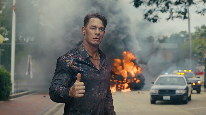 Peacemaker (John Cena) lets Harcourt (Jennifer Holland) know he's okay after stopping the Sons of Liberty in Peacemaker Season 2 Episode 3 "Another Rick Up My Sleeve" (2025), DC Studios