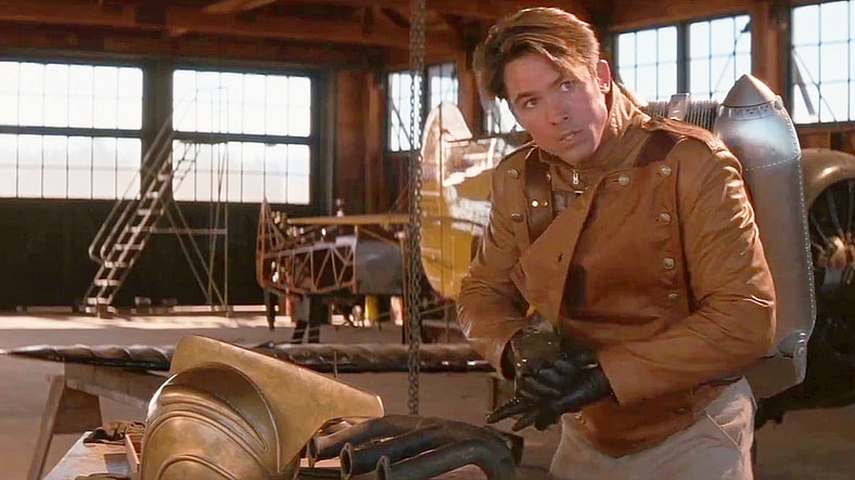 Cliff (Billy Campbell) suits up to save Malcom (Eddie Jones) from a potential plane crash in The Rocketeer (1991), Walt Disney Pictures
