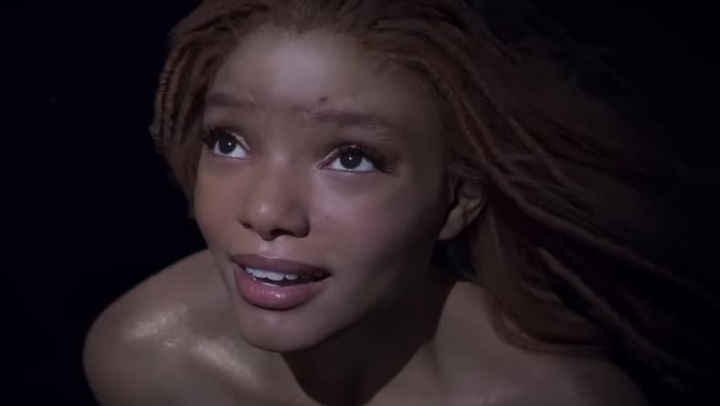 Ariel (Halle Bailey) takes notice of a naval battle happening above the surface in The Little Mermaid (2023), Disney