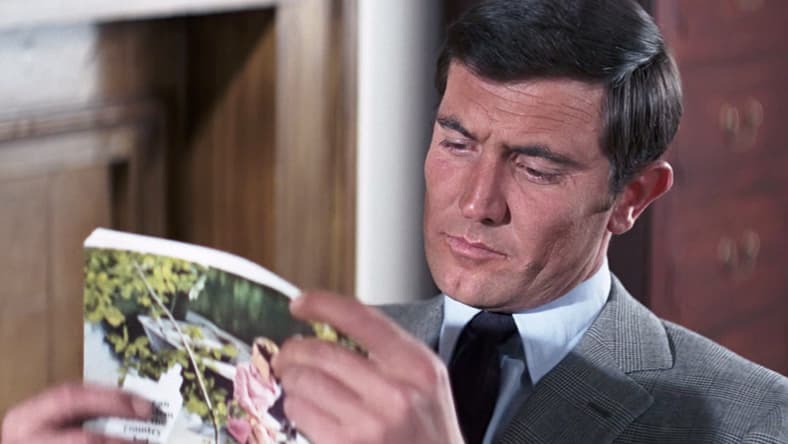 James Bond (George Lazenby) finds some light reading to pass the time in On Her Majesty's Secret Service (1969), United Artists