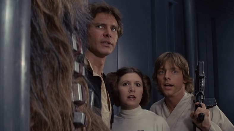 Chewbacca (Peter Mayhew), Han Solo (Harrison Ford), Princess Leia Organa (Carrie Fisher), and Luke Skywalker (Mark Hamill) plan their escape from the Death Star in Star Wars Episode IV: A New Hope (1977), Lucasfilm