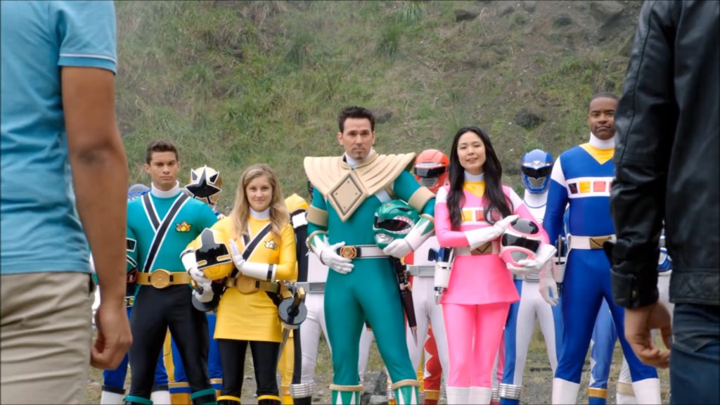 Tommy Oliver (Jason David Frank), TJ Johnson (Selwyn Ward), Cassie Chan (Patricia Ja Lee), Emily (Brittany Pirtle) e Mike (Hector David Jr.) lideram os antigos Rangers na batalha em Power Rangers Super Megaforce Temporada 1 Episódio 20 "Batalha Lendária" (2014), Saban Entertainment via Blu-ray