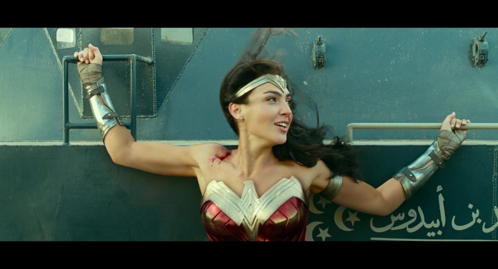 Diana (Gal Gadot) places herself between two armored vehicles in Wonder Woman 1984 (2020), via Warner Bros. Pictures Blu-ray