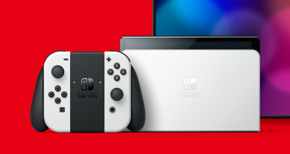 A Nintendo Switch OLED model on a red background. A TV can be partially seen with a blue and purple pattern on the screen via Nintendo