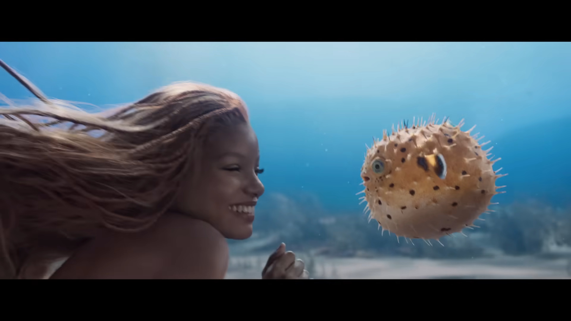 Ariel (Halle Bailey) plays with a puffer fish in The Little Mermaid (2023), Disney