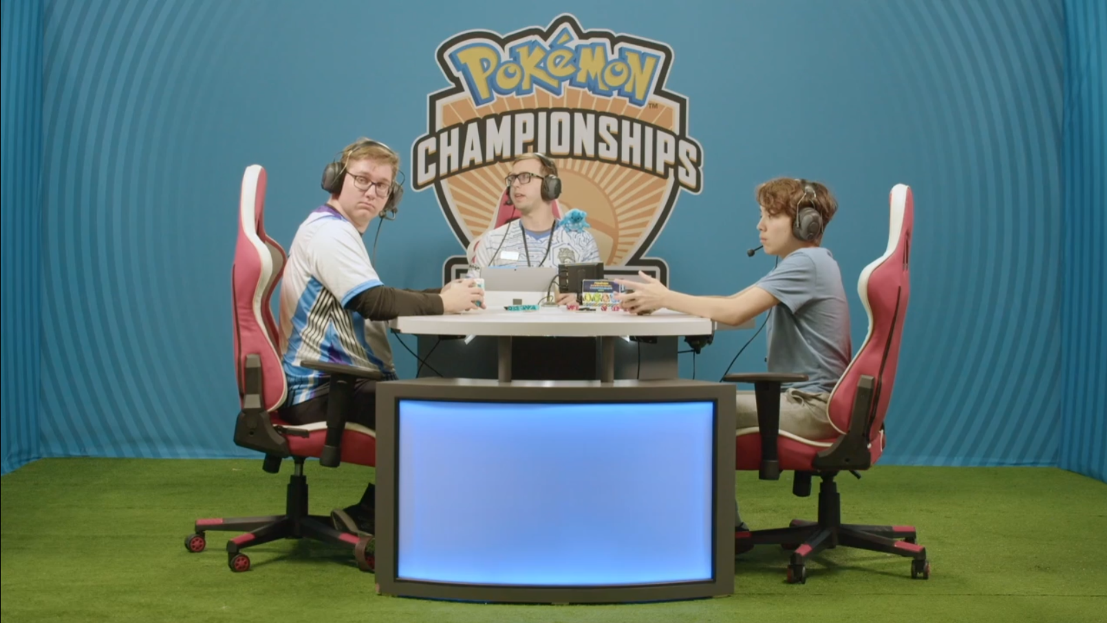 Makani Tran, Alex Schemanske, and a judge seem distracted by something out of frame via TCG Day 1 | 2023 Pokémon Charlotte Regional Championships, PokemonTCG Twitch