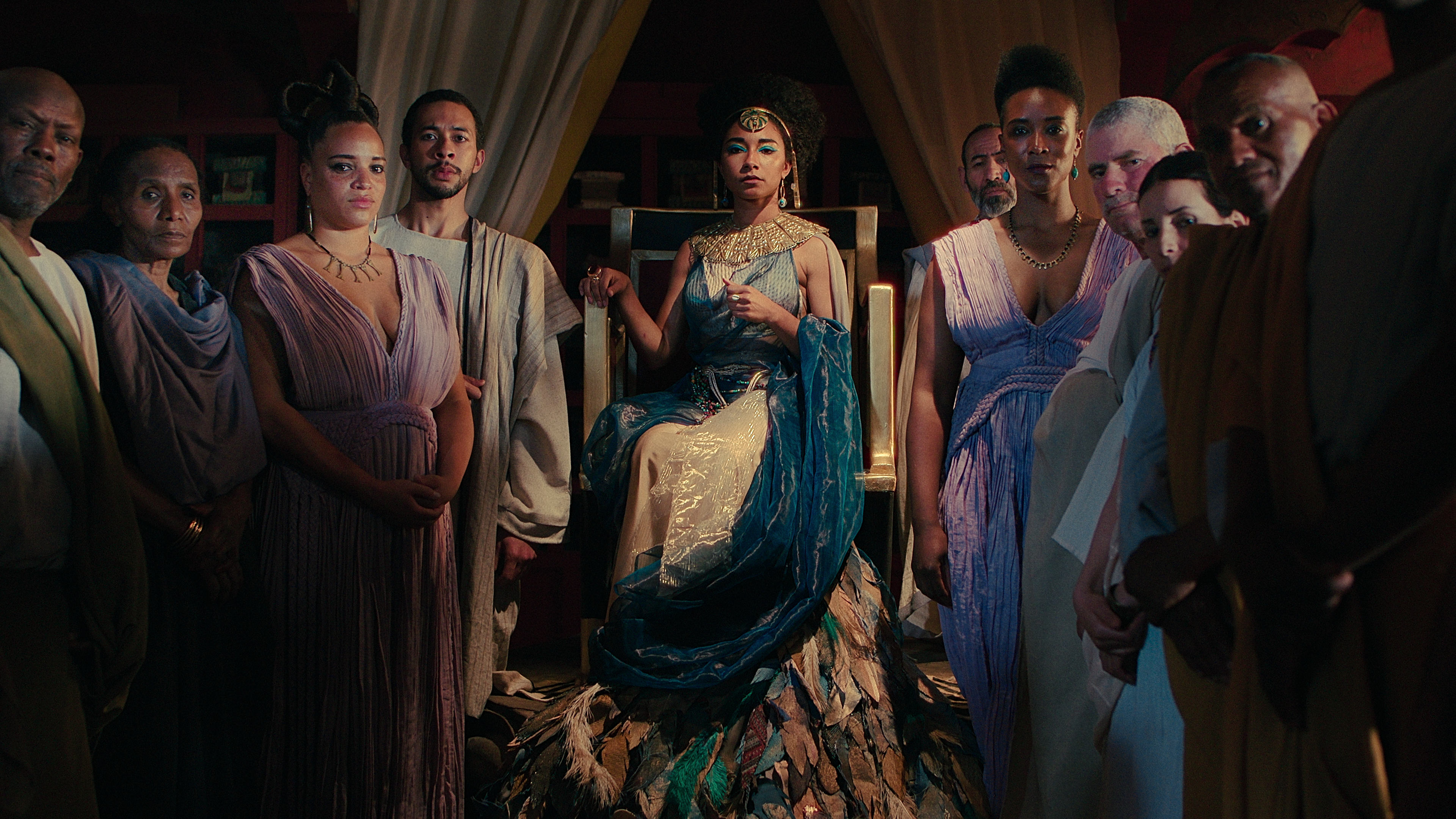 Cleópatra (Adele James) cercada por sua corte em Rainha Cleópatra (2023), Netflix