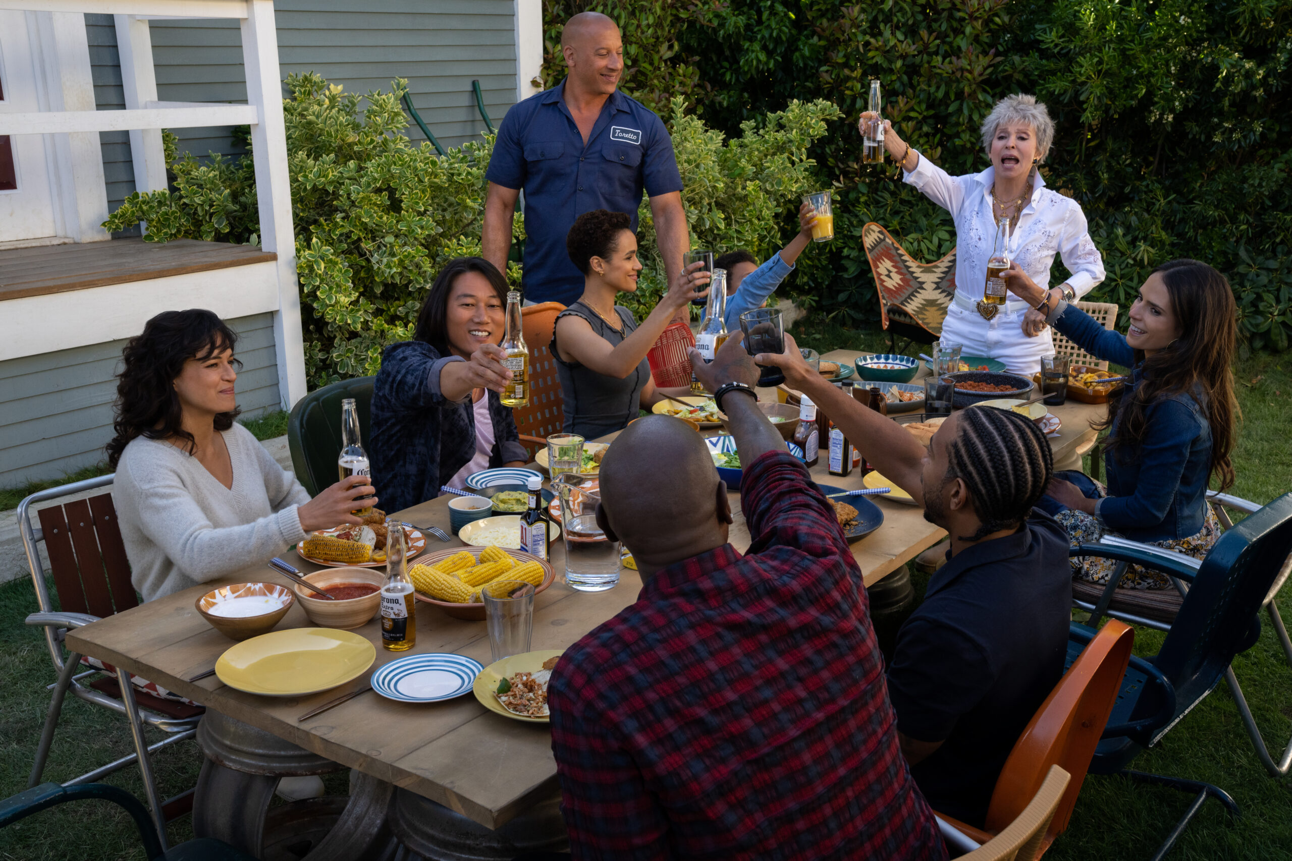 (clockwise, from left) Letty (Michelle Rodriguez), Han (Sung Kang), Ramsey (Nathalie Emmanuel), Dom (Vin Diesel), Little Brian (Leo Abelo Perry), Abuelita (Rita Moreno), Mia (Jordana Brewster), Tej (Chris ‘Ludacris’ Bridges, back to camera) and Roman (Tyrese Gibson, back to camera) in Fast X, directed by Louis Leterrier.