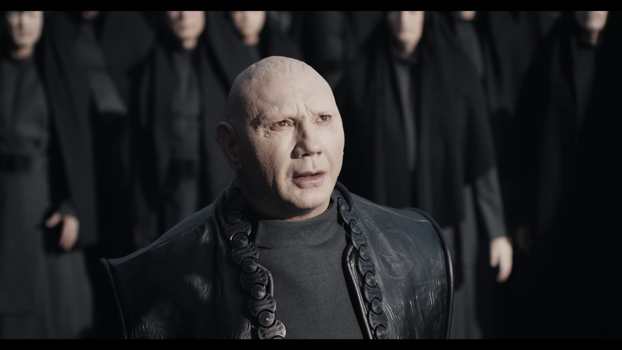 Glossu Rabban (Dave Bautista) watches on as his uncle, The Baron (Stellan Skarsgård), addresses the crowds in Dune: Part Two (2023), Warner Bros. Discovery
