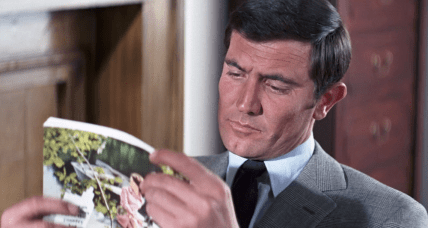 James Bond (George Lazenby) finds some light reading to pass the time in On Her Majesty's Secret Service (1969), United Artists