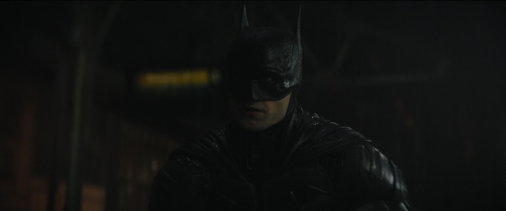 Batman (Robert Pattinson) reveals himself to a gang attempting a robbery in The Batman (2022), Warner Bros. Pictures
