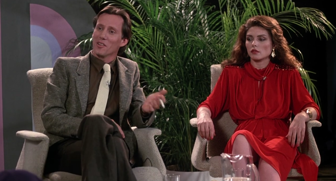 Max Renn (James Woods) e Nicki Brand (Debbie Harry) debatem sobre degeneração em talk show no Videodrome (1983), Universal Pictures