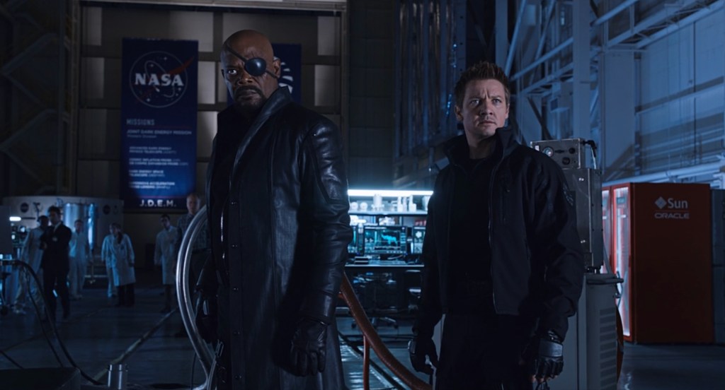 Nick Fury (Samuel L. Jackson) and Clint Barton (Jeremy Renner) pay close attention to the Tesseract in The Avengers (2012), Marvel Studios
