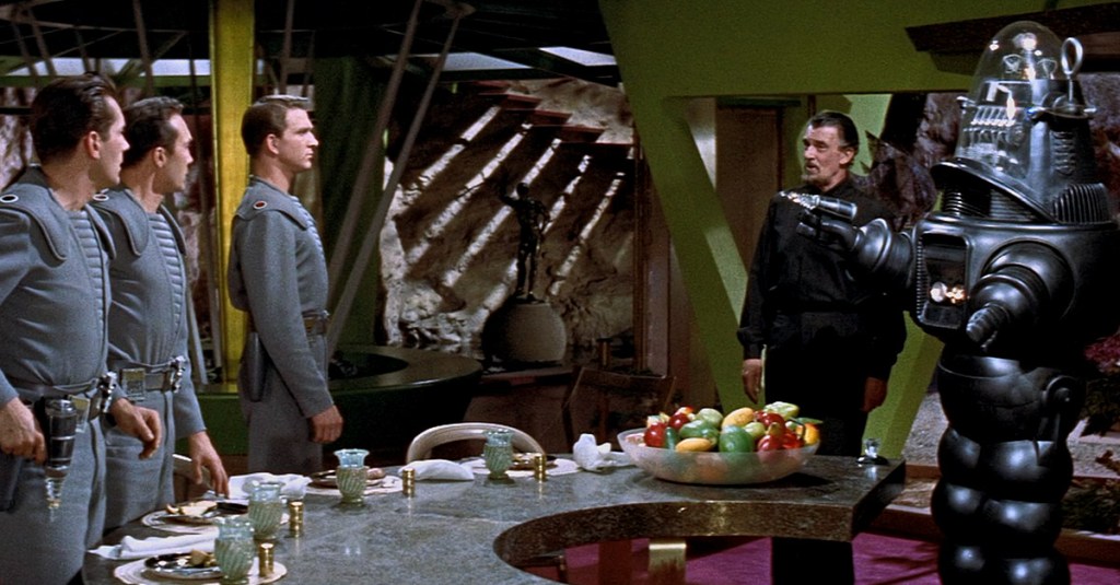 Dr. Morbius (Walter Pidgeon) demonstrates Robby the Robot's programming on Commander Adams (Leslie Nielsen) in Forbidden Planet (1956), Metro-Goldwyn-Mayer
