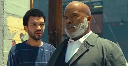 Justice Smith as Aren and David Alan Grier as Roger in The American Society of Magical Negroes (2024), Focus Features