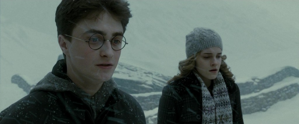 Harry (Daniel Radcliffe and Hermione (Emma Watson) watch as Katie Bell (Georgina Leonidas) is tortured by the Opal Necklace in Harry Potter and the Half-Blood Prince (2009), Warner Bros. Pictures