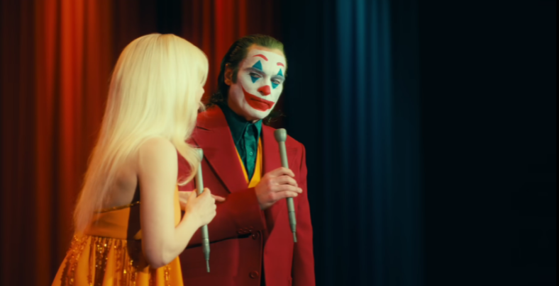 Arthur (Joaquin Phoenix) listens to Harleen (Lady Gaga) tell a joke in Joker: Folie à Deux (2024), Warner Bros. Pictures