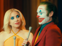 Arthur (Joaquin Phoenix) invites Harleen (Lady Gaga) to introduce their next bit in Joker: Folie à Deux (2024), Warner Bros. Pictures